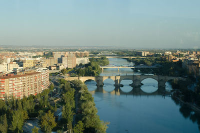 Bridge over river in city against sky