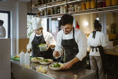 Male and female chefs preparing food at commercial kitchen in restaurant