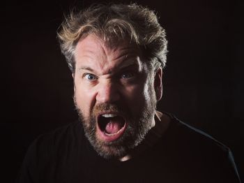 Portrait of man shouting against black background