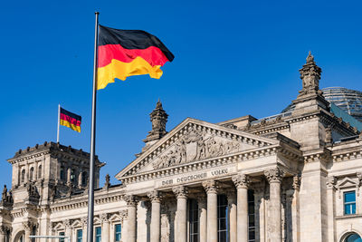 Low angle view of flags against blue sky