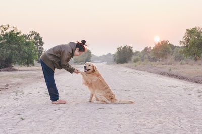 Man with dog on road against sky