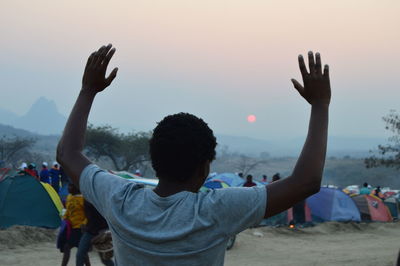 Rear view of people at beach against sky during sunset