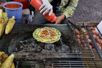 Man preparing vietnamese pizza on barbecue grill