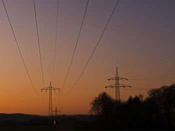 Silhouette electricity pylon against sky during sunset