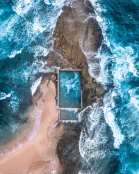 Aerial view of waves splashing on rocks at beach