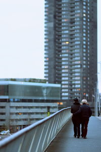 Rear view of woman walking on bridge in city