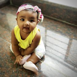 Portrait of cute baby girl sitting on floor at home