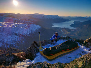 Explorer and sleeping bag on top of snow capped mountain 