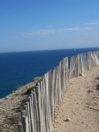 Wooden posts on beach against sky