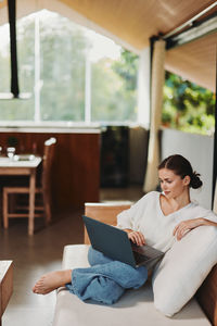 Young woman sitting on sofa at home