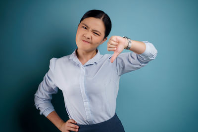 Smiling young woman standing against blue background