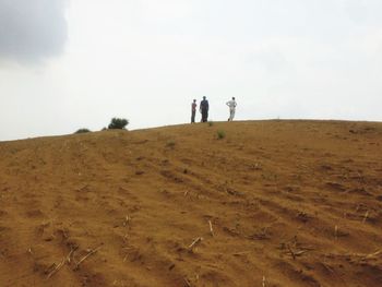 People walking on desert against clear sky