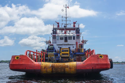 Red ship moored on sea against sky