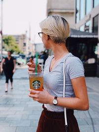 Midsection of woman holding umbrella standing in city