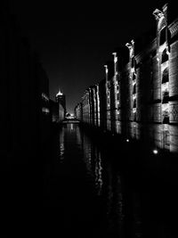 Illuminated buildings by river against sky at night