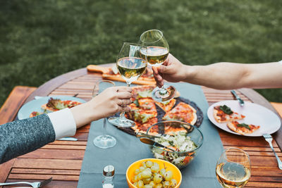 Friends making toast during summer picnic outdoor dinner in a home garden