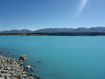 Scenic view of sea and mountains against clear blue sky