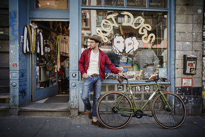 Germany, hamburg, st. pauli, man with bicycle waiting in front of vintage shop