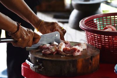 Close-up of woman cutting meat with knife on board