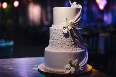 Wedding venue - green and purple restaurant hall, with neon lighting, white three tiered cake.