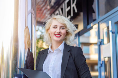 Portrait of businesswoman standing against building