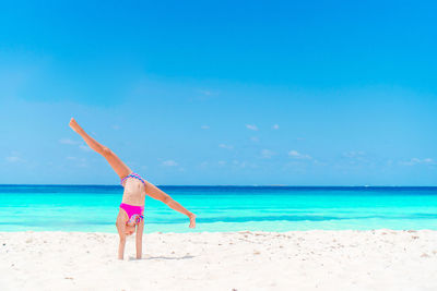 Woman with umbrella on beach against blue sky