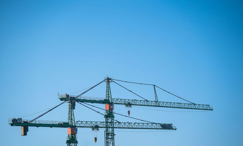 Low angle view of crane against clear blue sky