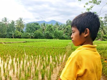 A small child standing on the edge of the rice field, enjoying the mountain view