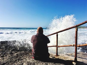 Rear view of man looking at sea against clear sky