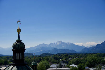 Church by buildings against clear blue sky