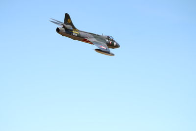 Low angle view of helicopter flying against clear blue sky