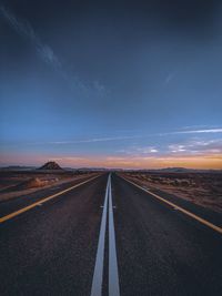 Surface level of road against sky during sunset