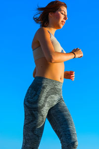 Low angle view of woman standing against blue sky