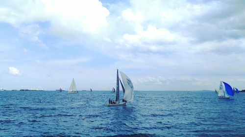 Boat sailing in sea against cloudy sky