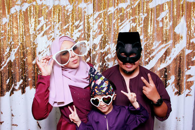 Confident family wearing novelty items against corrugated wall