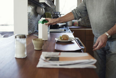 Midsection of senior man preparing breakfast at kitchen counter