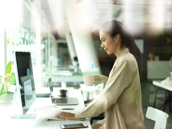 Side view of woman using smart phone on table