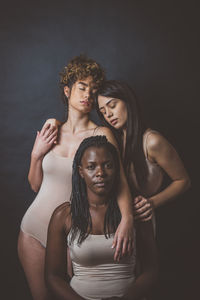 Portrait of young couple standing against black background