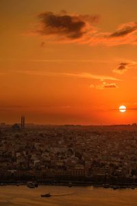 Aerial view of townscape by sea against orange sky