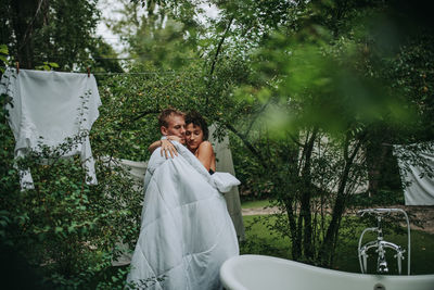 Couple with towel standing against trees