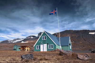 Flag on house by mountain against sky