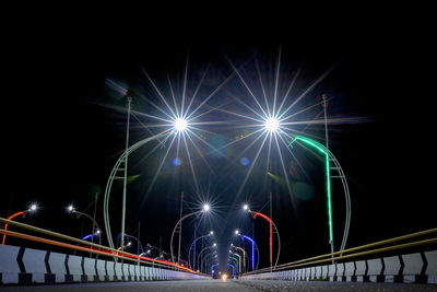 Low angle view of light trails on footbridge at night
