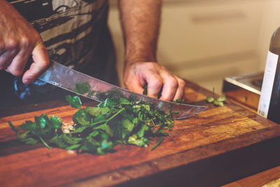 Midsection of man cutting vegetables on cutting board in kitchen