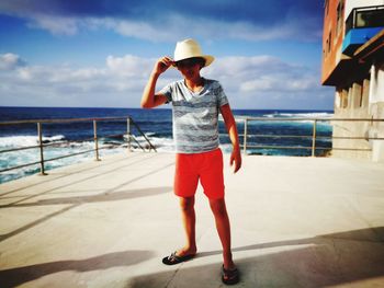 Full length of child standing on sea shore against sky