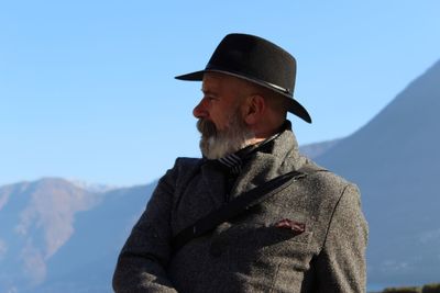 Senior man wearing hat while standing against mountain