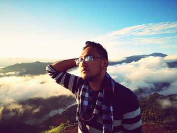 Young man wearing sunglasses standing against sky