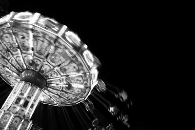 Low angle view of illuminated lighting equipment against black background