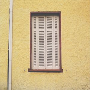Close-up of window on yellow wall