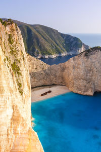 Scenic view of sea by mountains against sky