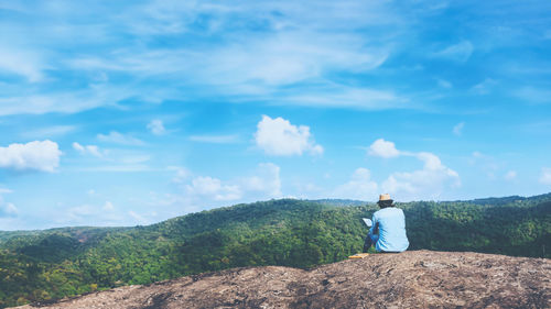 Rear view of man standing on mountain against sky